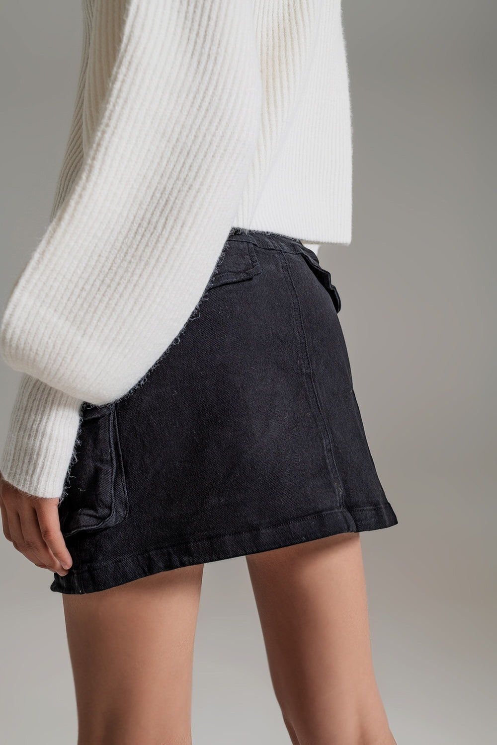 Vista lateral de falda denim negra mini corte pitillo.