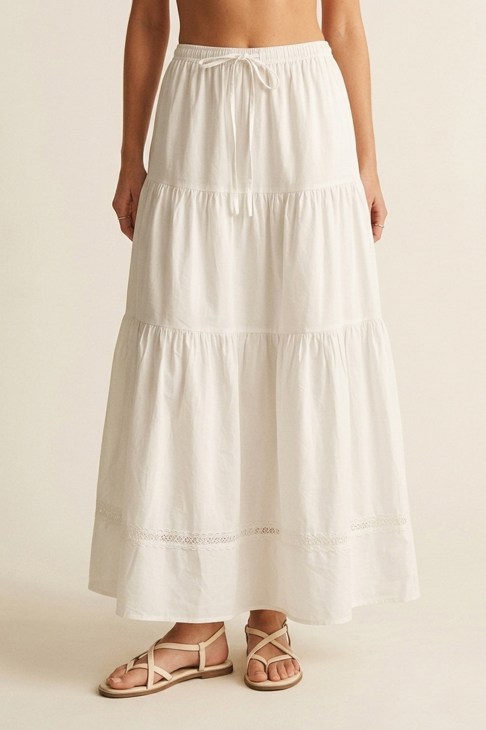 Vista frontal de falda larga blanca de algodón con cintura elástica y diseño escalonado.