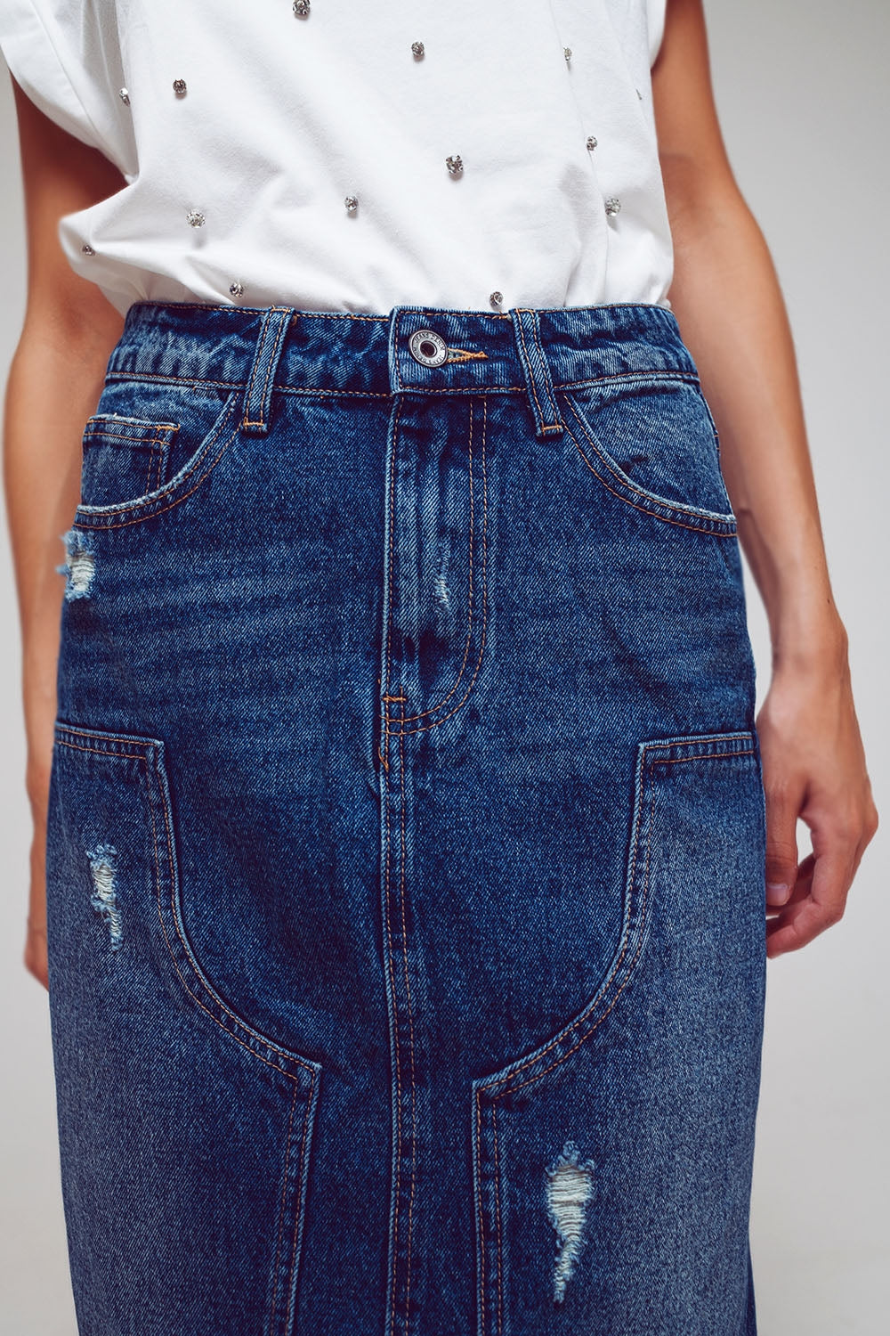 Detalle de la cintura y los paneles de una falda vaquera larga de denim rígido.