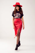 Falda midi de satén roja para mujer con abertura lateral y detalle de pedrería, combinada con camiseta rockera y sombrero rojo.