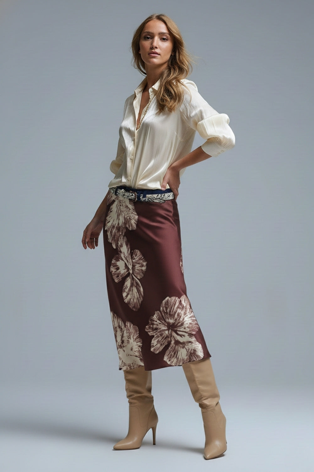 falda midi satinada color burdeos con flores grandes, camisa crema y botas altas beige.