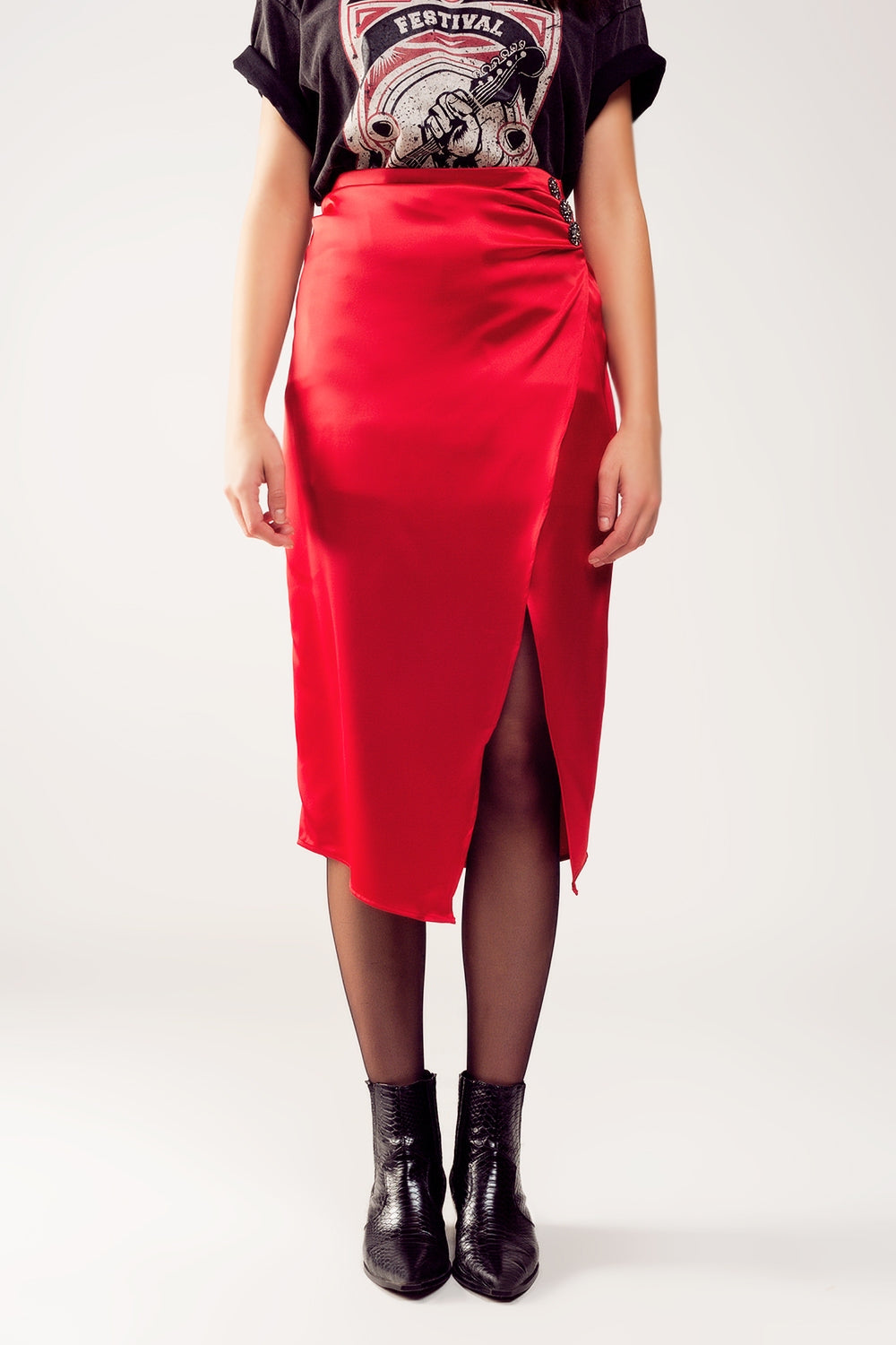 Falda midi de satén roja para mujer con abertura lateral y detalle de pedrería, combinada con camiseta rockera y sombrero rojo.