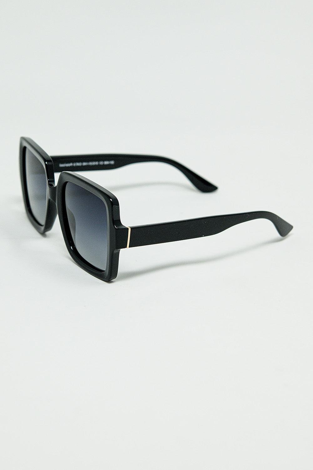 Gafas de sol de montura cuadrada ancha con detalle dorado en las patillas.