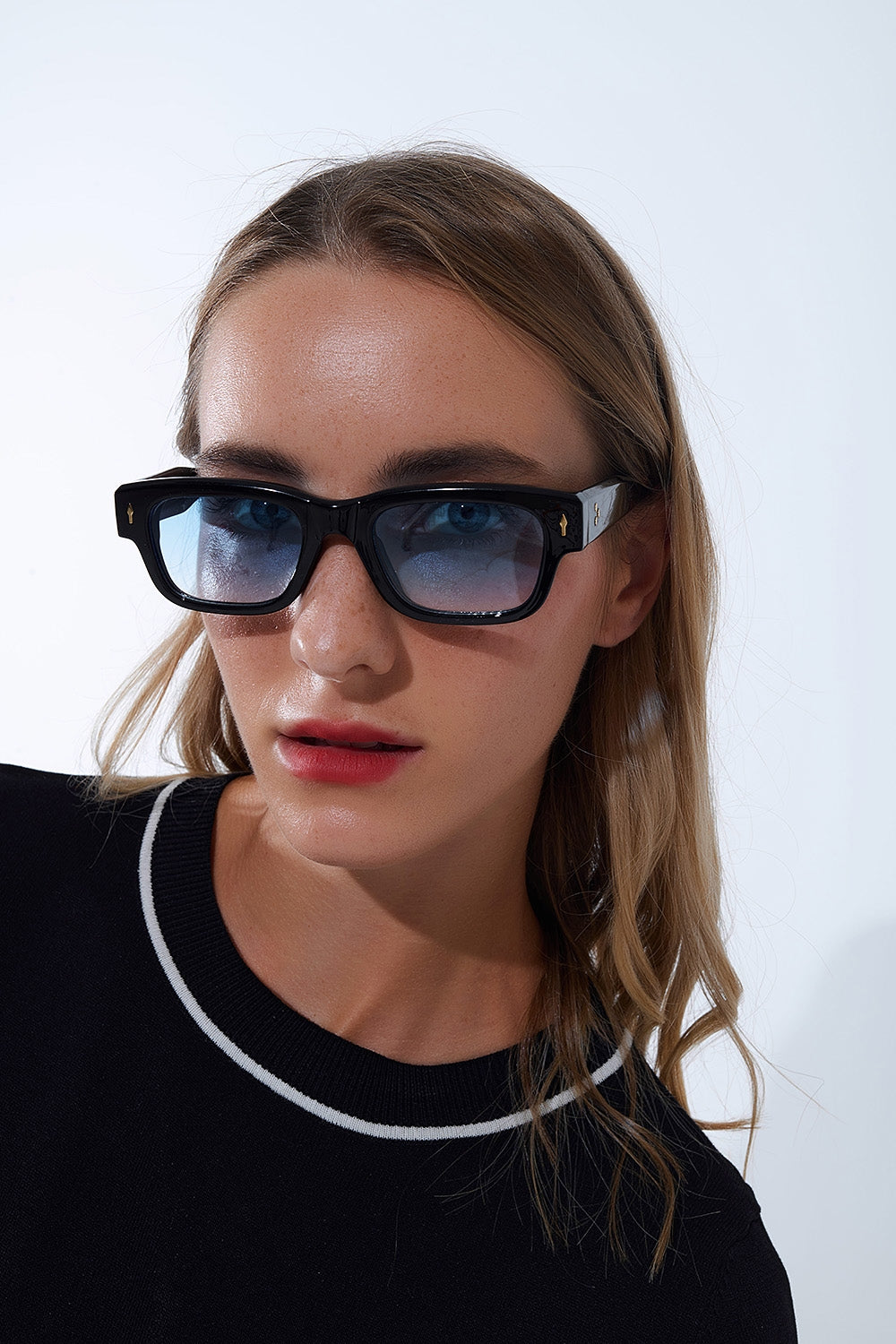 Gafas de sol negras con montura ovalada con detalle dorado y cristal azul