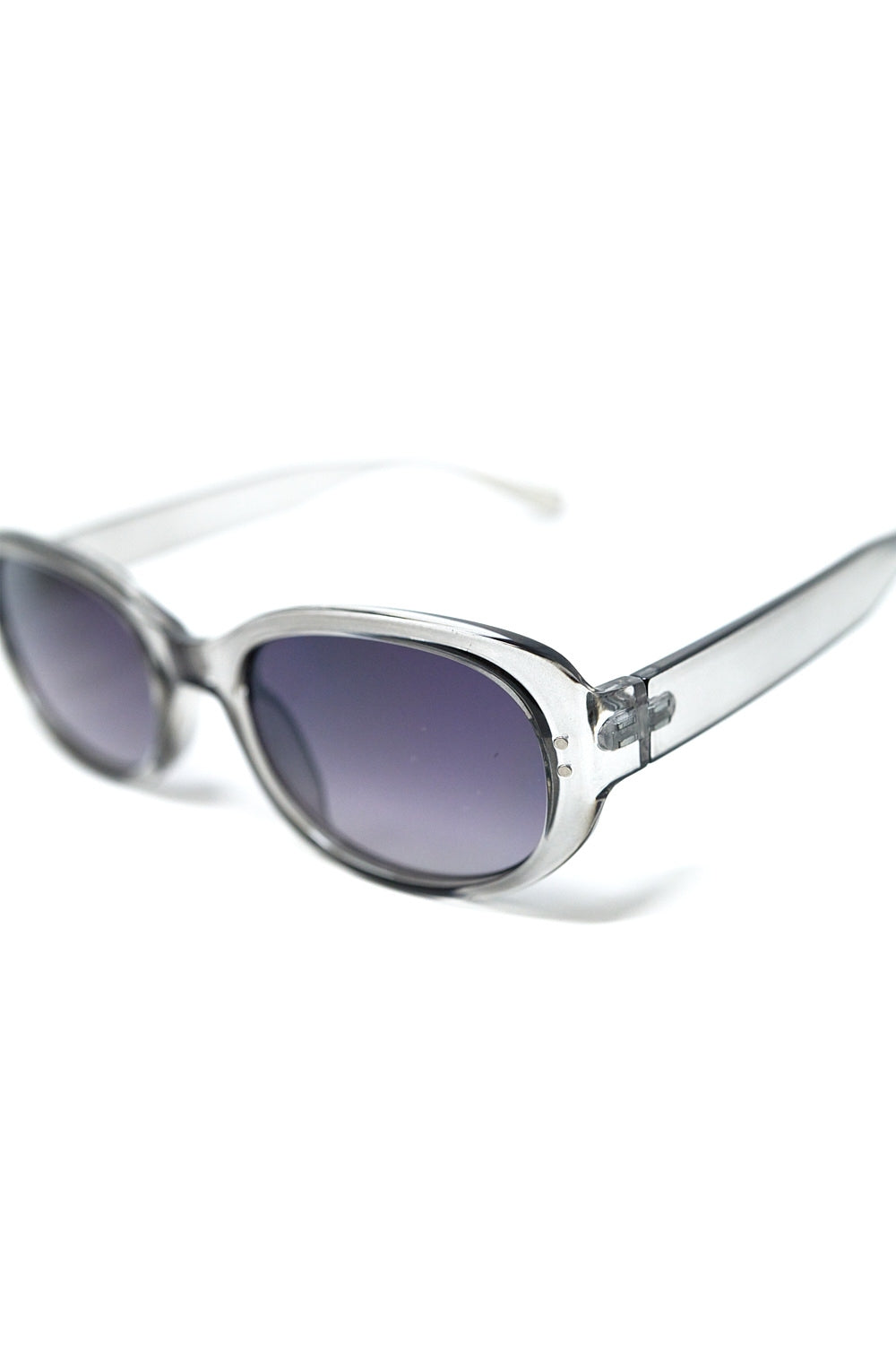 Gafas de sol ovaladas con montura gris translúcida y lentes negras degradadas detalle.
