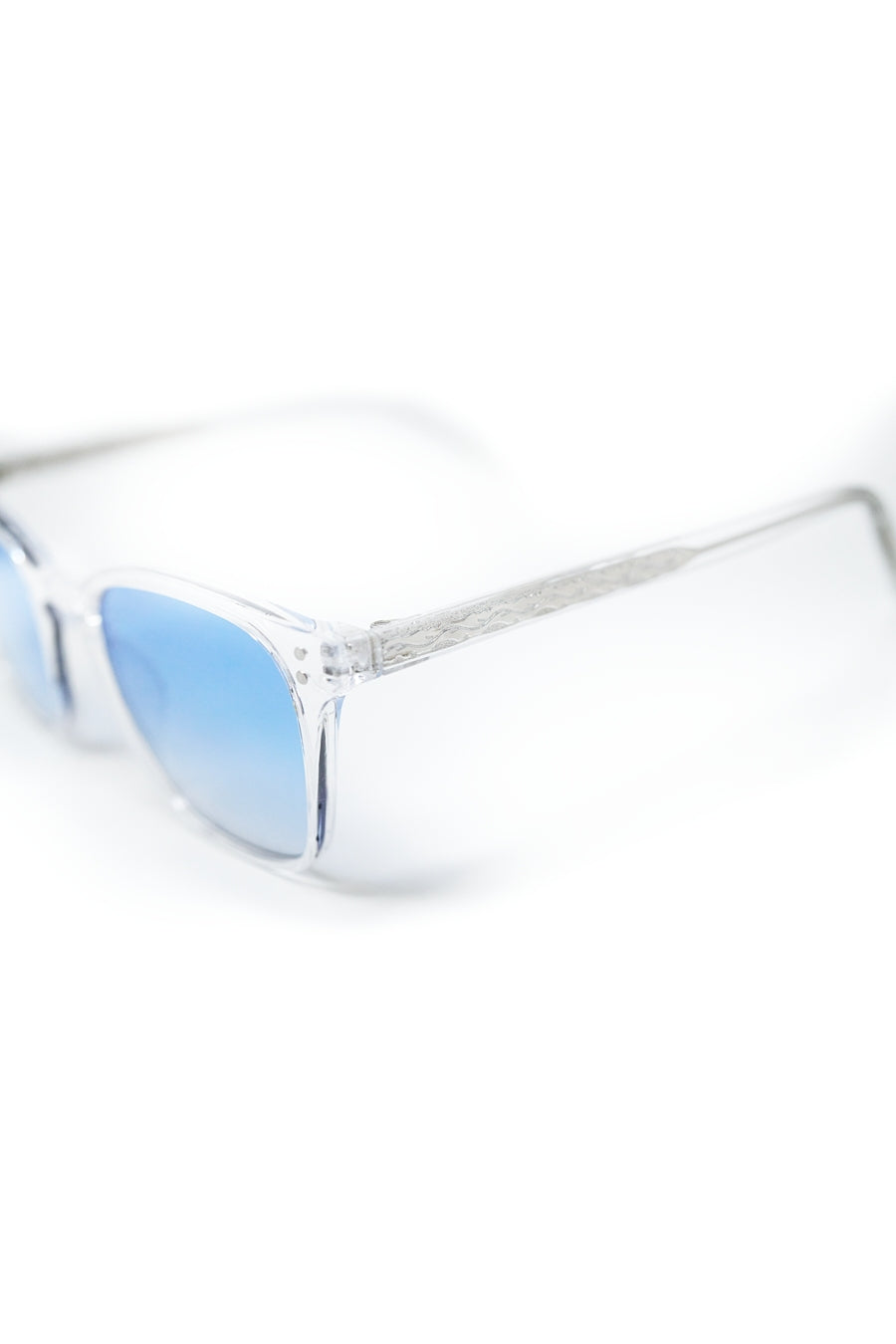 Gafas de sol cuadradas con montura transparente y lentes azul claro degradadas vista en ángulo.