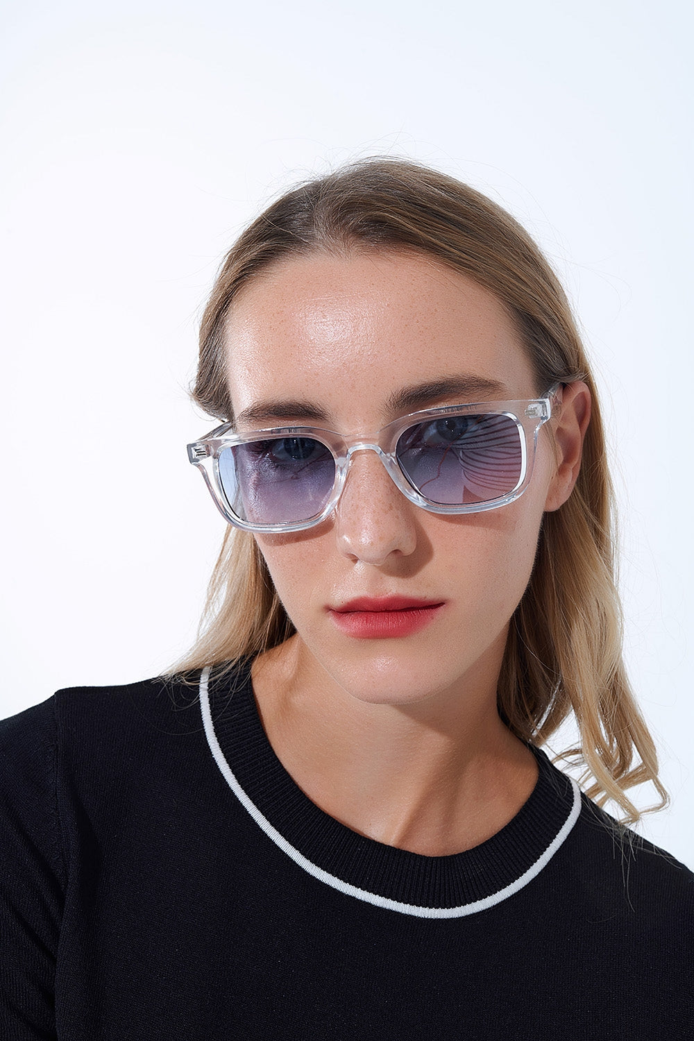 Modelo con gafas de sol cuadradas transparentes y lentes azules degradadas vista frontal.