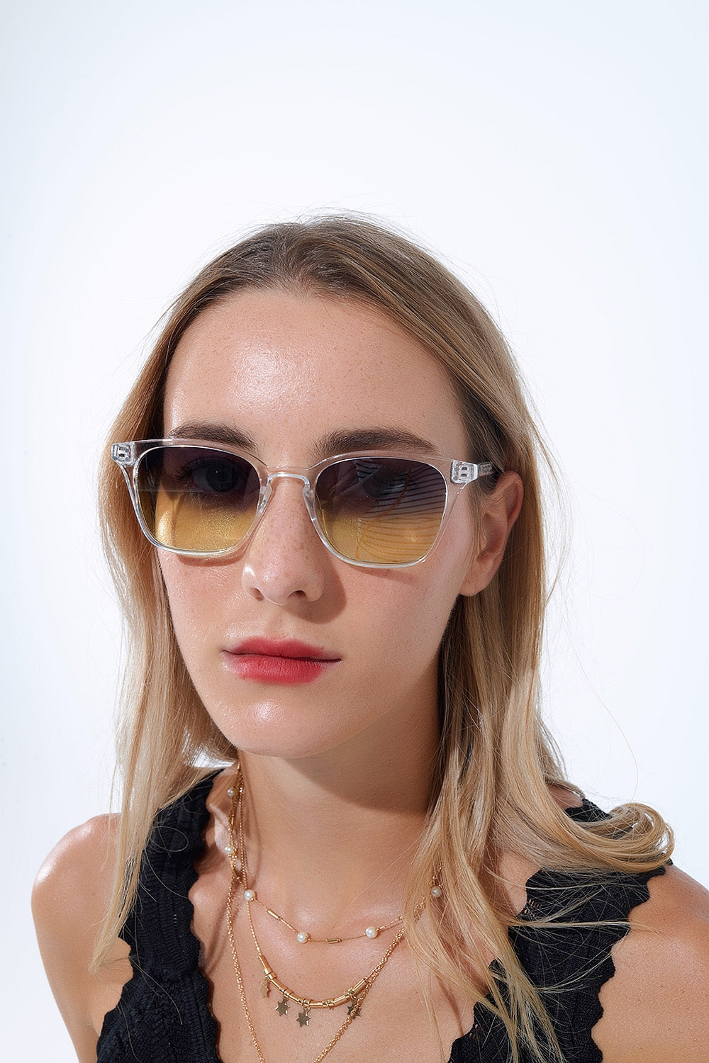 Mujer con gafas de sol cuadradas montura transparente y lentes verdes degradadas.