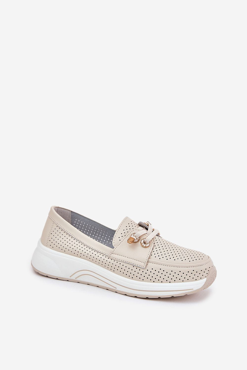 Vista lateral de las sneakers beige con detalles metálicos, en conjunto casual.