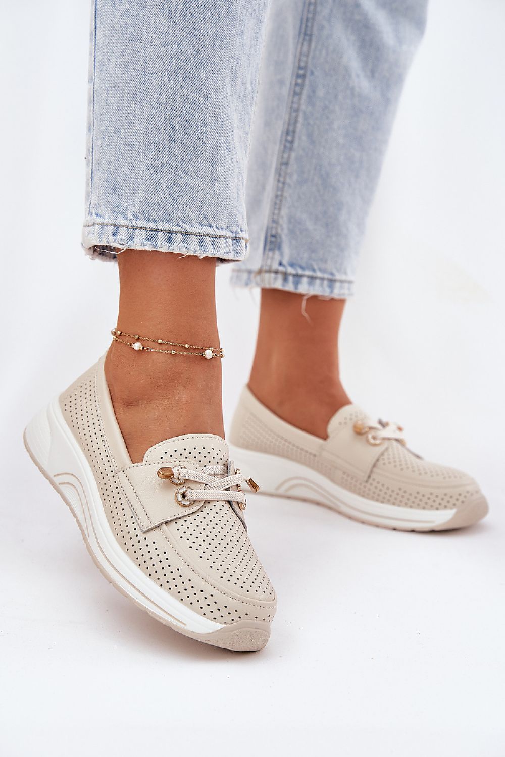 Sneakers en uso combinadas con vaquero claro, vista frontal con detalles brillantes en primer plano.