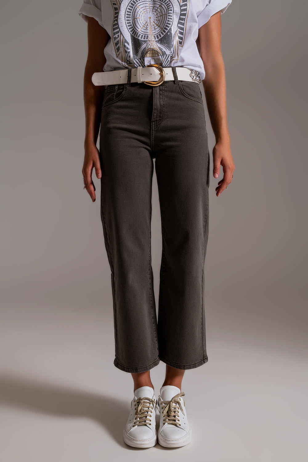 Plano frontal completo de mujer con vaqueros anchos grises largo capri y zapatillas blancas.