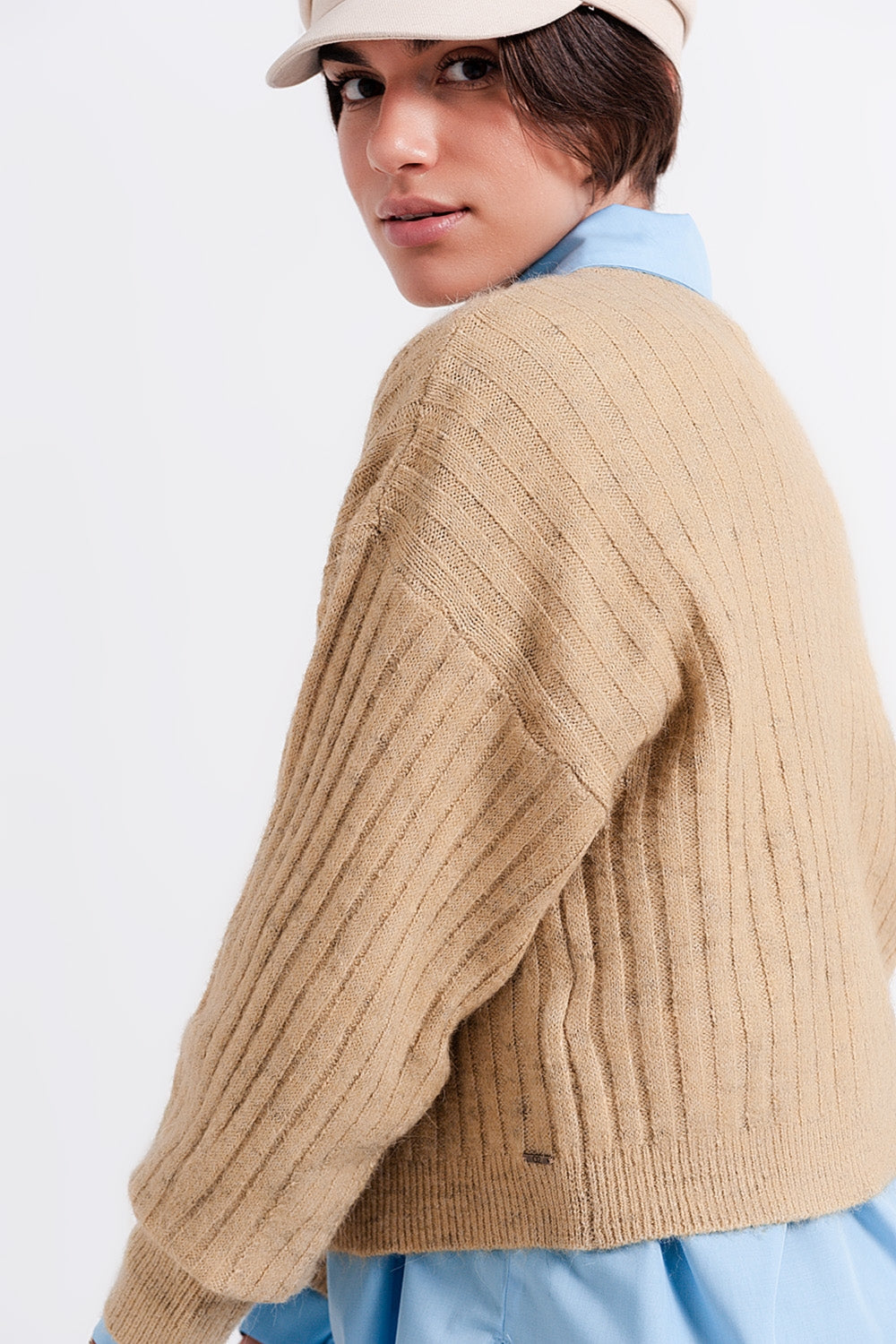 Vista perfil de un jersey cropped de punto de canalé en color beige.