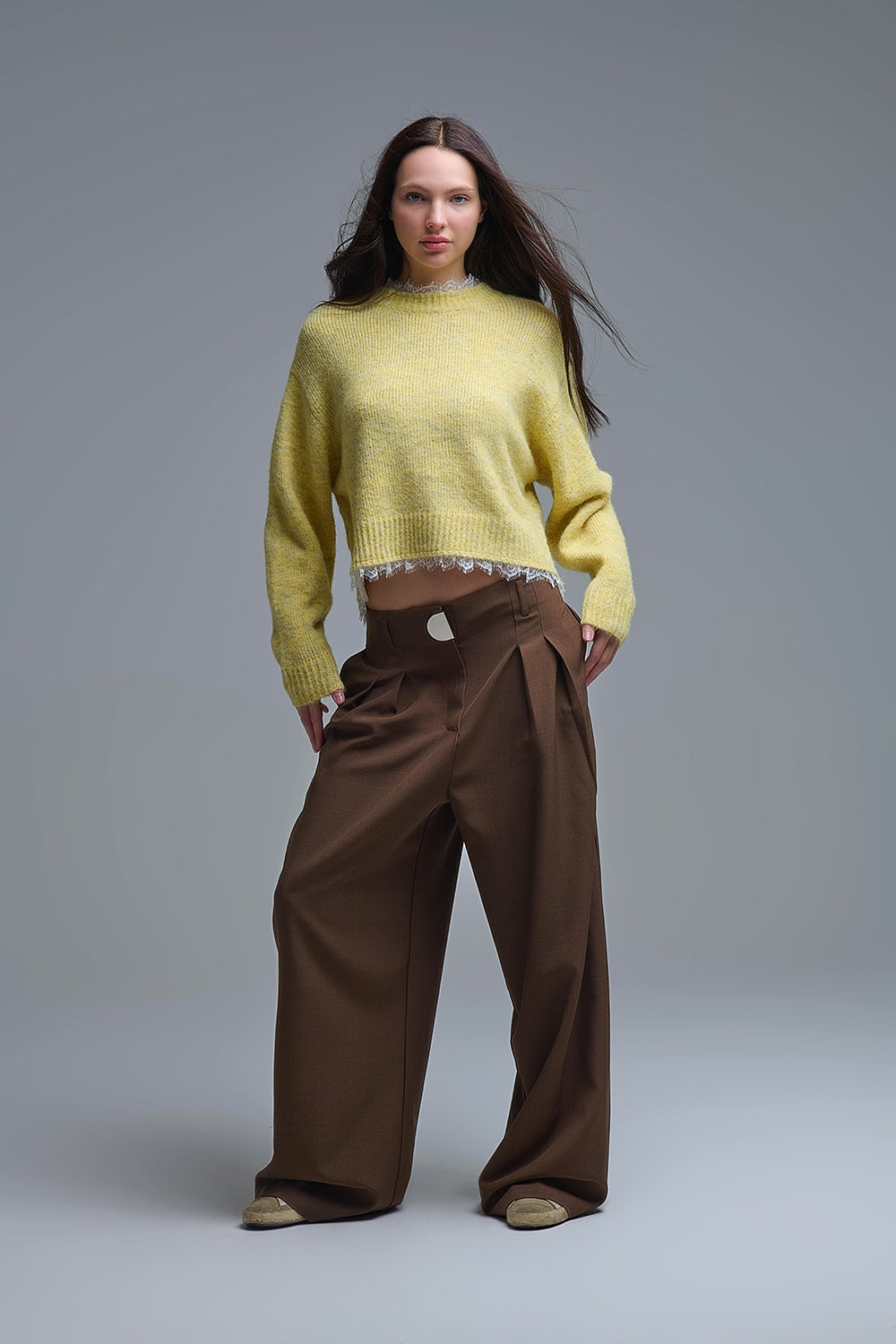 Modelo con jersey corto de punto amarillo pastel con borde de encaje en cuello y bajo.