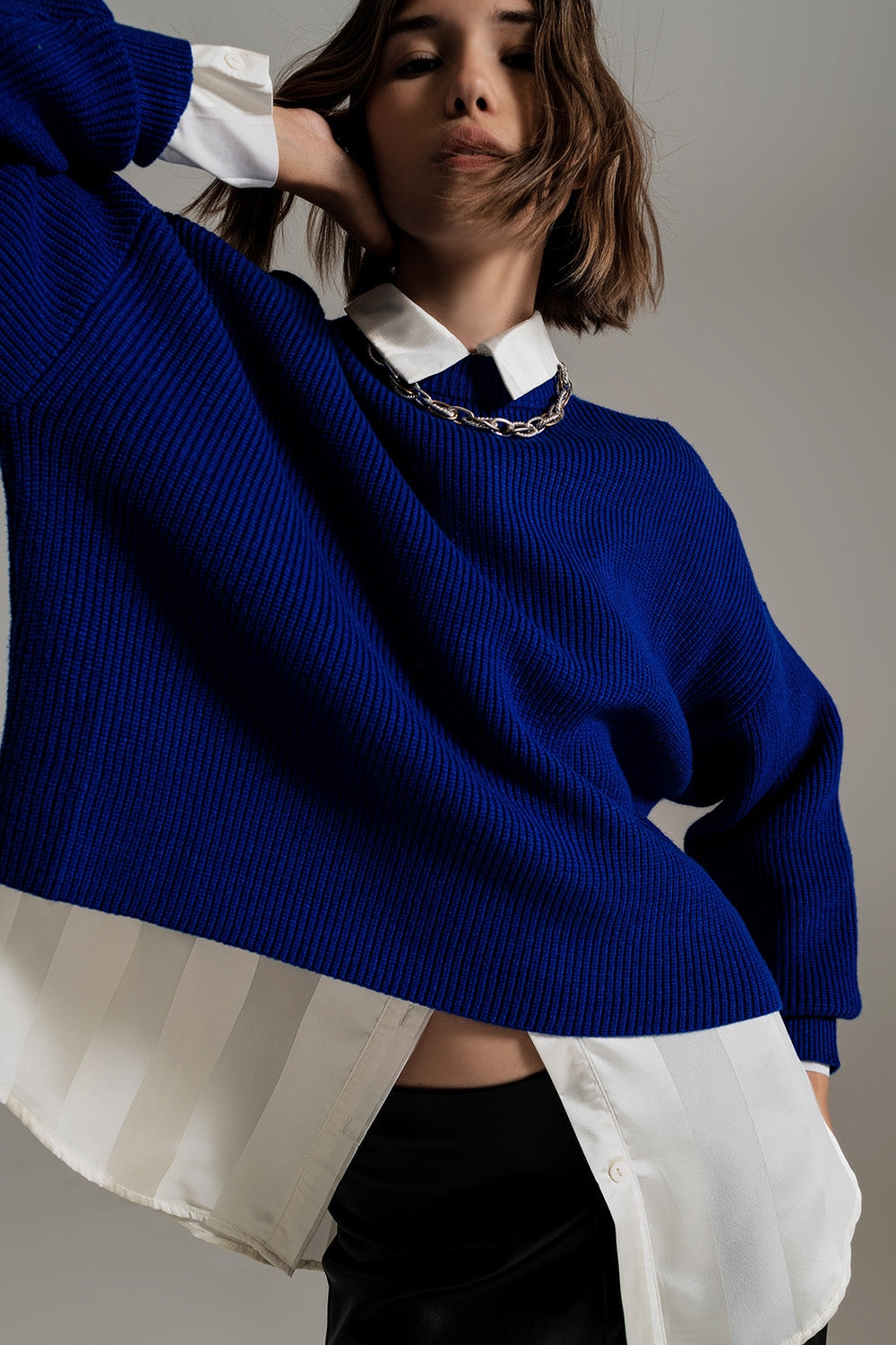 jersey oversize de punto grueso en color azul cobalto, sobre una camisa blanca.