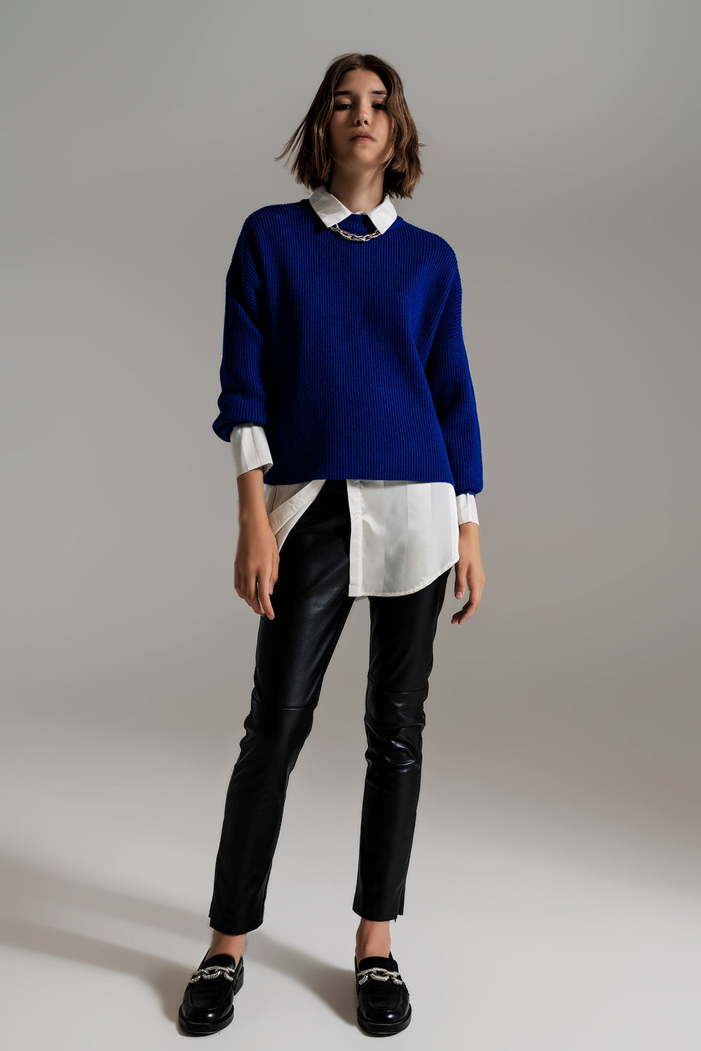 Modelo con jersey oversize de punto grueso en color azul cobalto, sobre una camisa blanca.