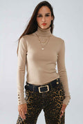 jersey beige de cuello alto con botones dorados en el puño 