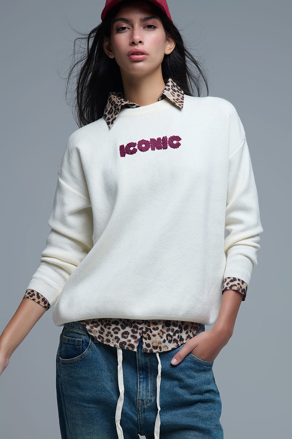jersey de punto crema con "ICONIC" en rizo y una lista de ciudades "Global Tour" bordada.