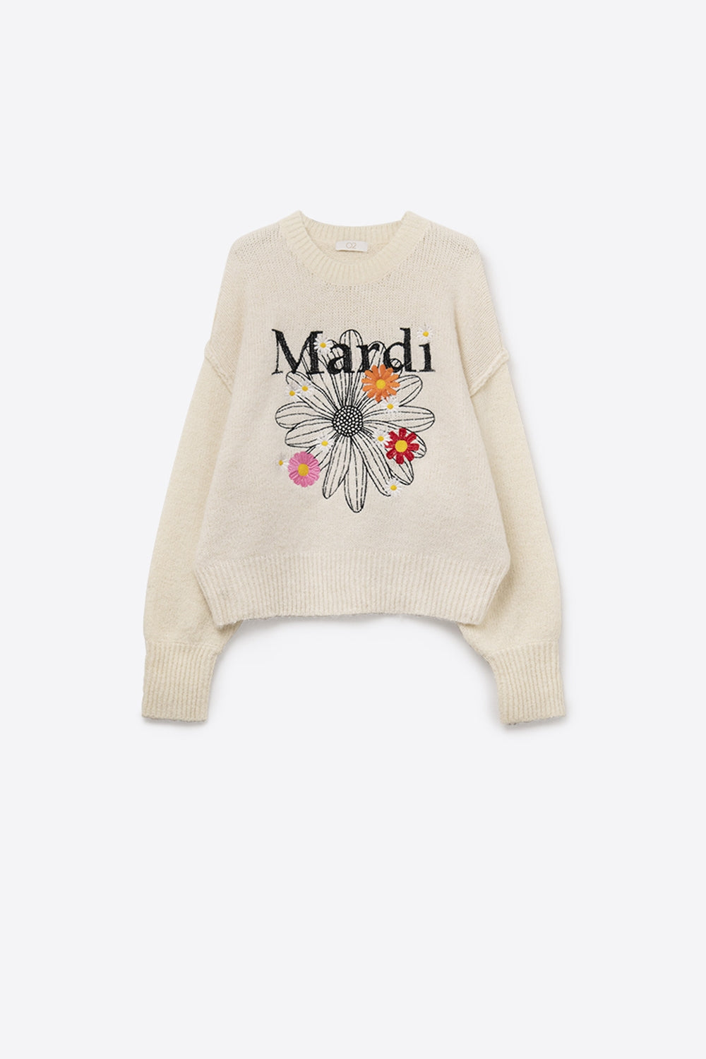 Foto de producto (flat lay) de un jersey de punto crema con gráfico "Mardi" y flores bordadas sobre fondo blanco.
