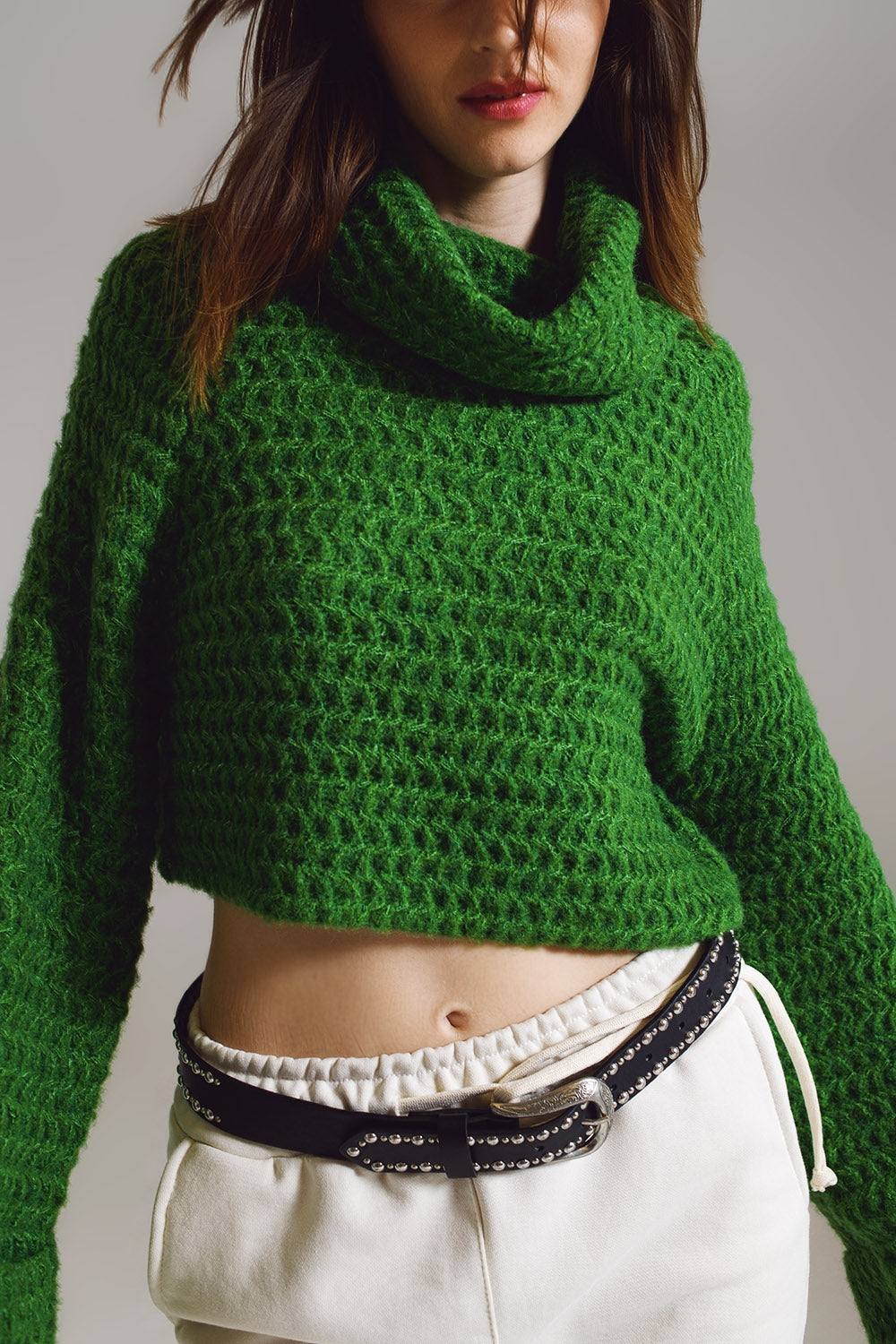 Modelo con jersey cropped de punto gofre en color verde esmeralda y pantalones blancos.