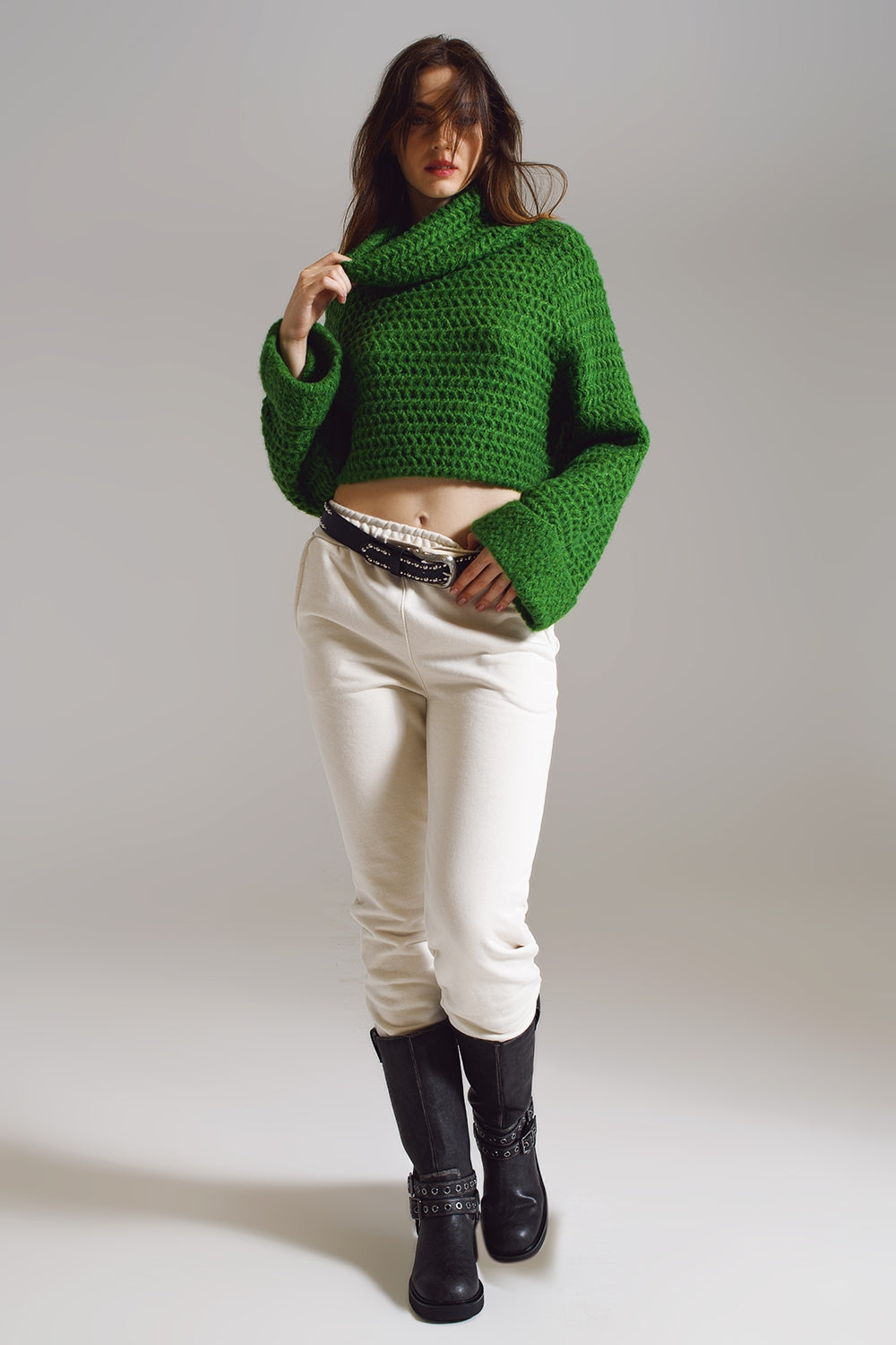 Modelo con jersey cropped de punto gofre en color verde esmeralda y pantalones blancos.