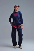 Modelo con jersey oversize de punto en color azul marino, con el texto "ICONIC" bordado en el pecho.