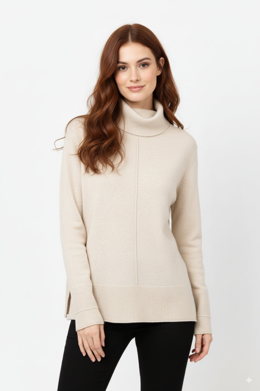Modelo con jersey oversize de punto suave y cuello vuelto en color beige, combinado con pantalones negros.