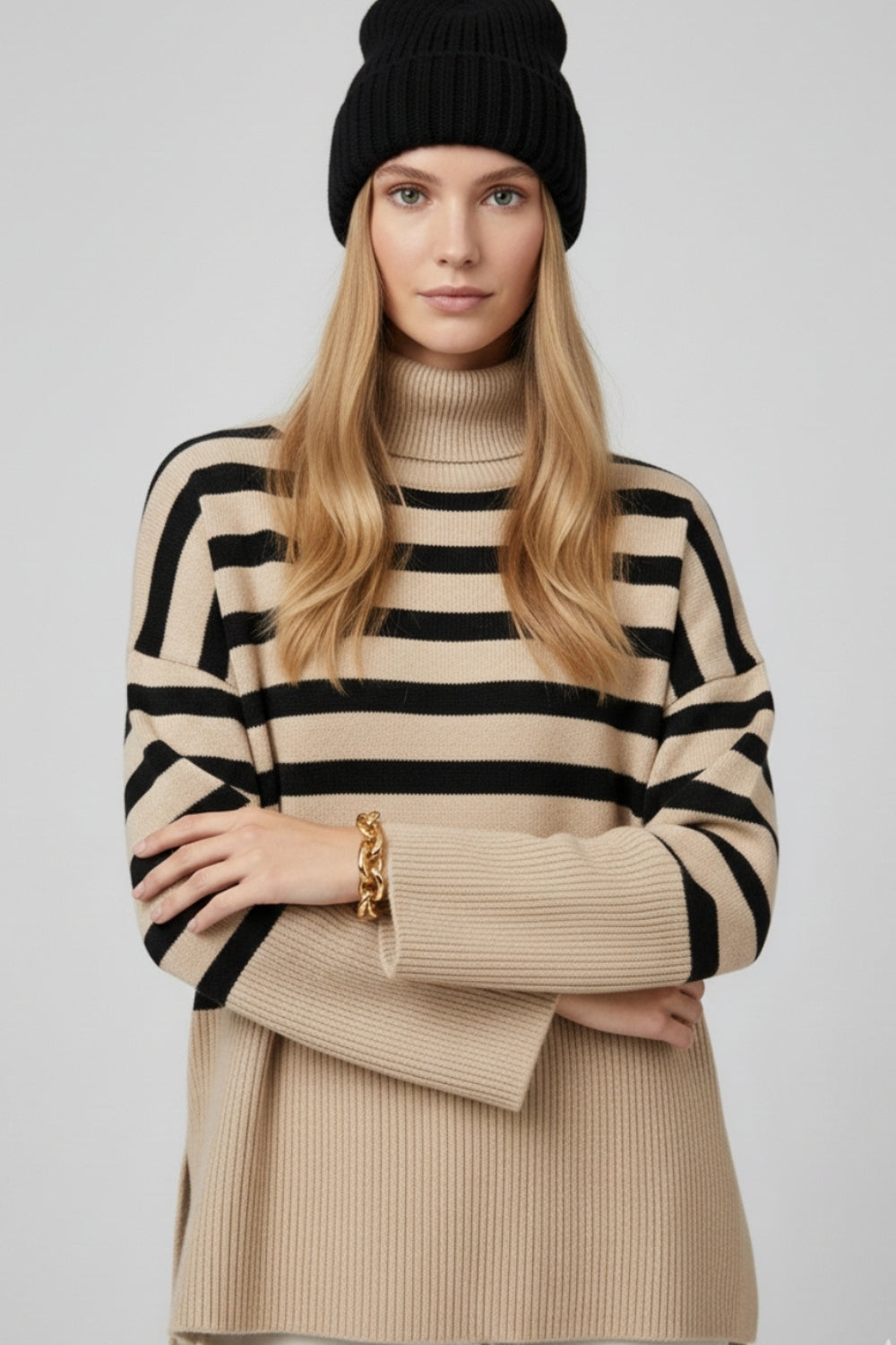 Modelo con jersey oversize de cuello vuelto en color beige con rayas negras horizontales.