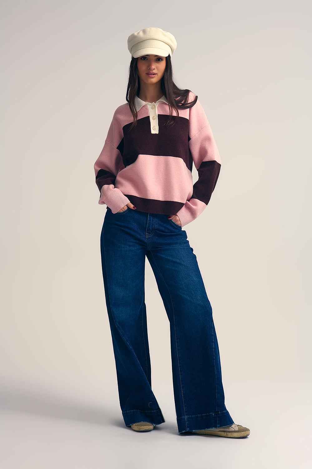 Mujer con boina crema vistiendo jersey estilo polo rugby de rayas anchas rosas y marrones con cuello blanco.