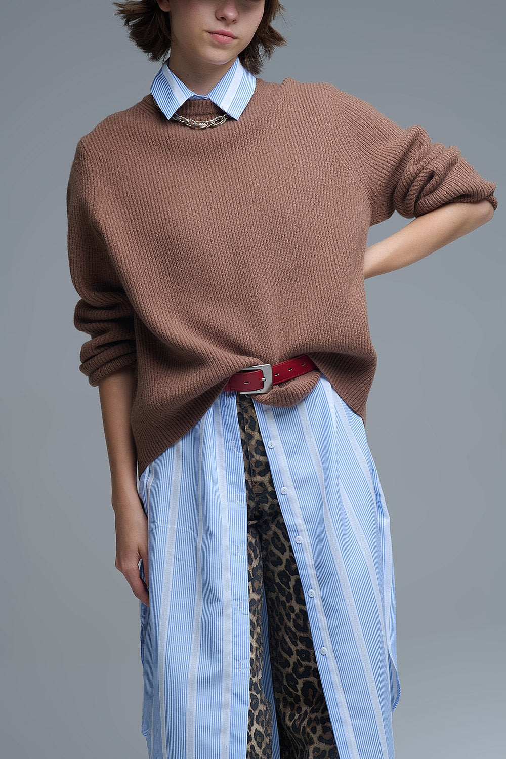 Modelo con jersey de punto acanalado en color camel, de corte amplio y cuello redondo, sobre una camisa de rayas.