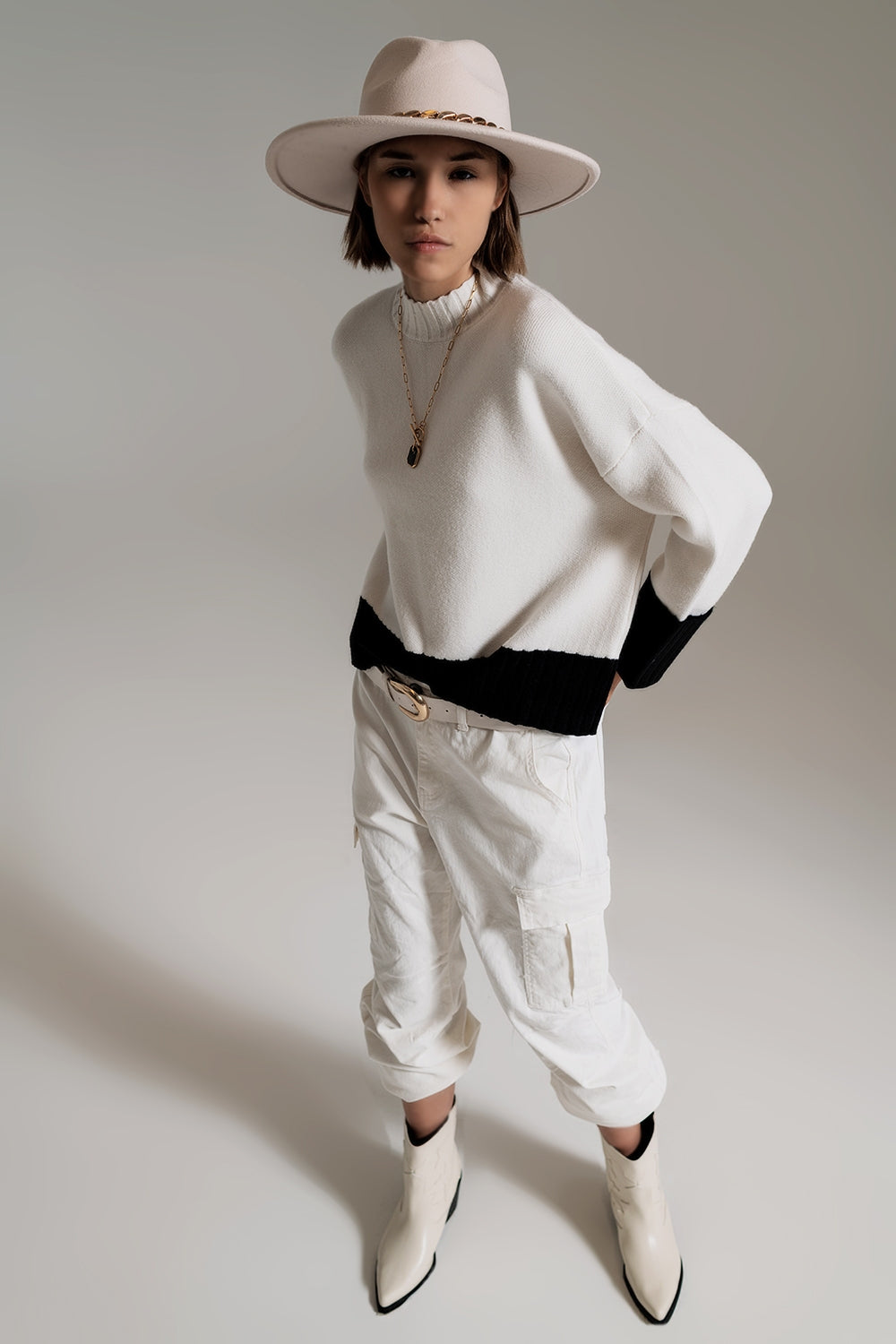 Look de cuerpo entero con jersey de punto color block en blanco y negro, pantalones cargo blancos y botas.