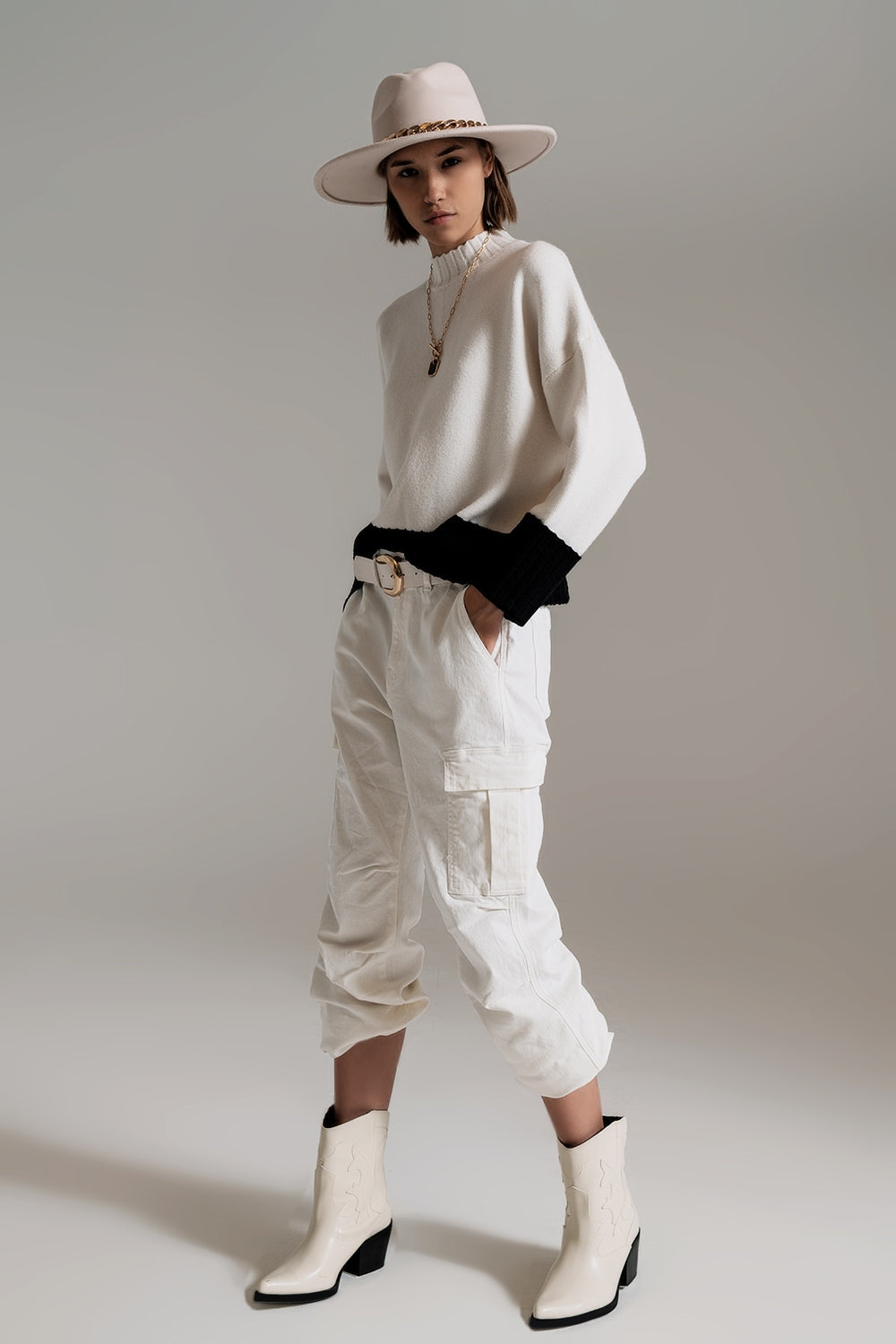Look de cuerpo entero con jersey de punto color block en blanco y negro, pantalones cargo blancos y botas.