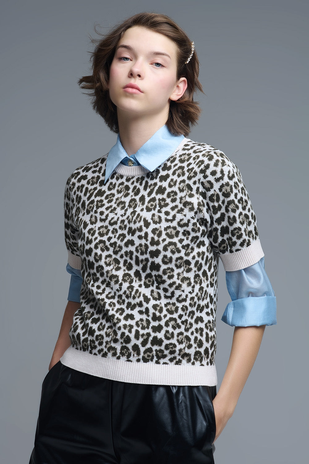 Modelo con jersey de punto de manga corta con estampado de leopardo, llevado sobre una camisa azul.