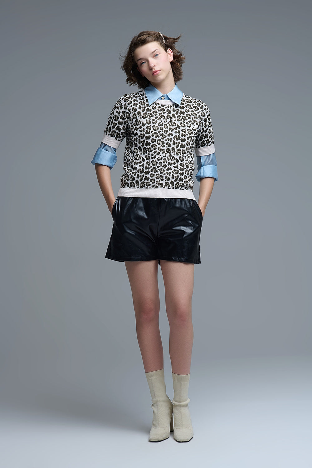 Modelo con jersey de punto de manga corta con estampado de leopardo, llevado sobre una camisa azul.