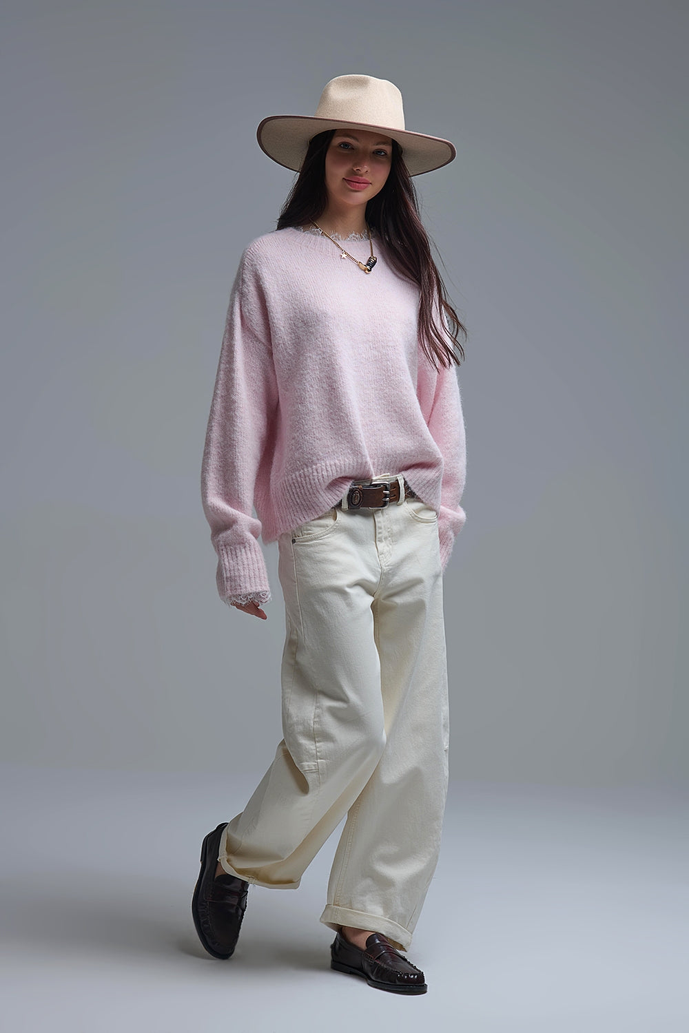 Look completo de mujer con jersey rosa oversize con encaje, vaqueros anchos beige, cinturón marrón y mocasines.