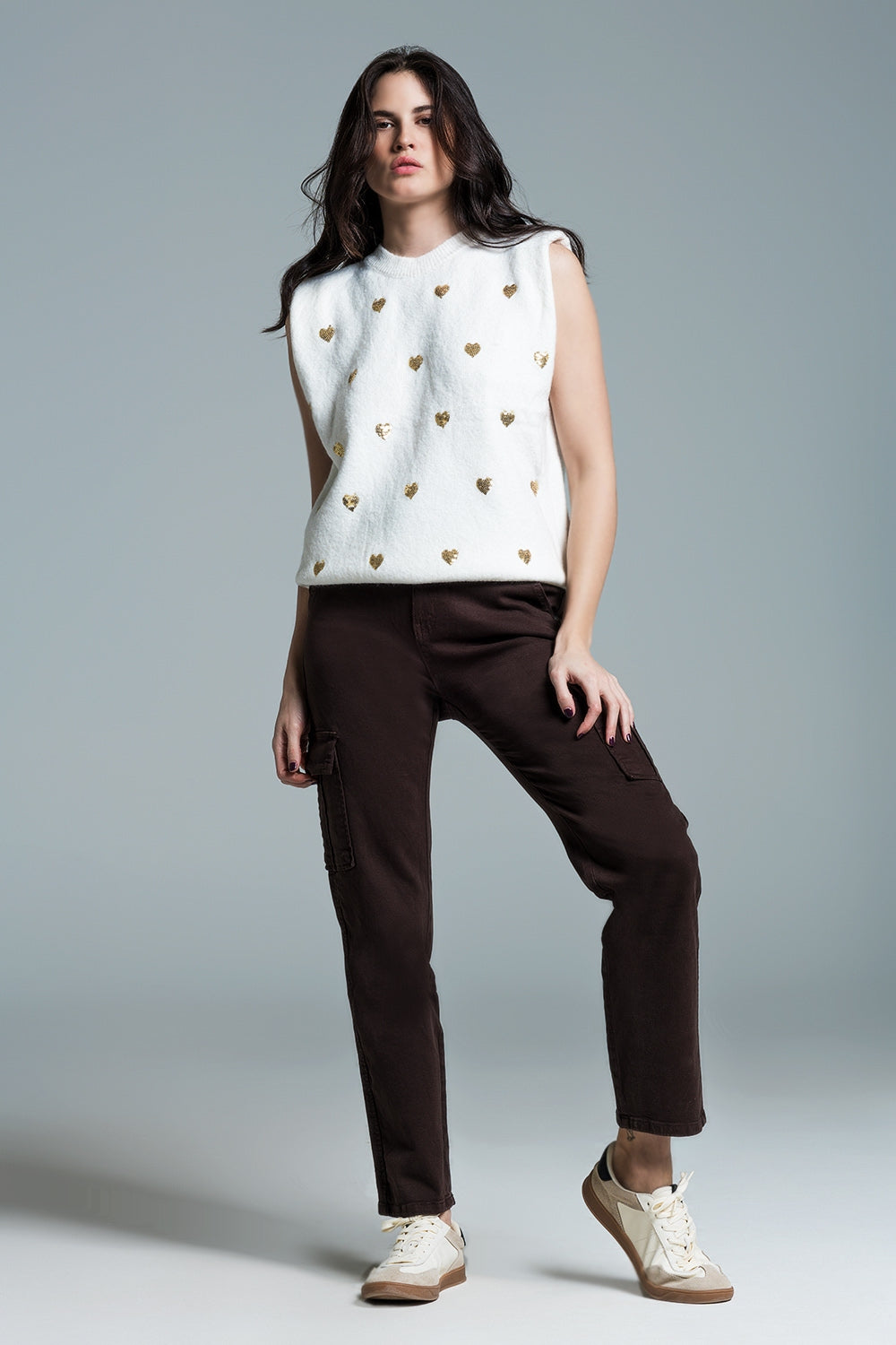 Look completo de un jersey sin mangas blanco con corazones de lentejuelas y un pantalón marrón.