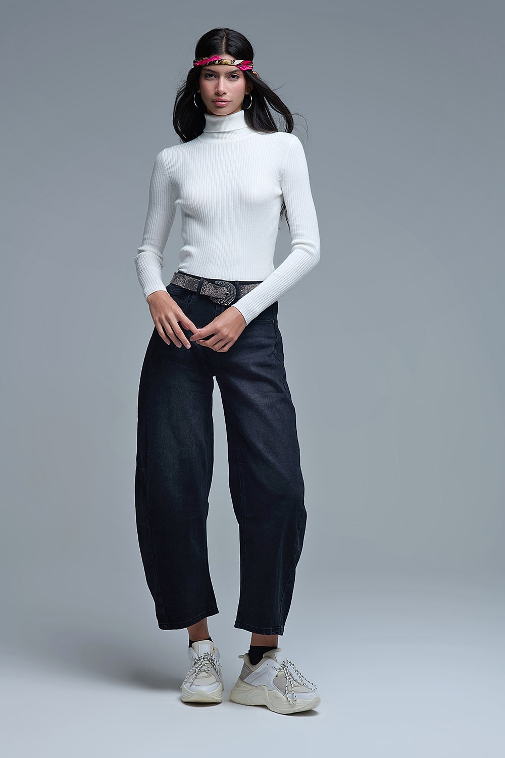 Look completo de mujer con jersey blanco bodycon, vaqueros anchos negros, zapatillas chunky y pañuelo en la cabeza.