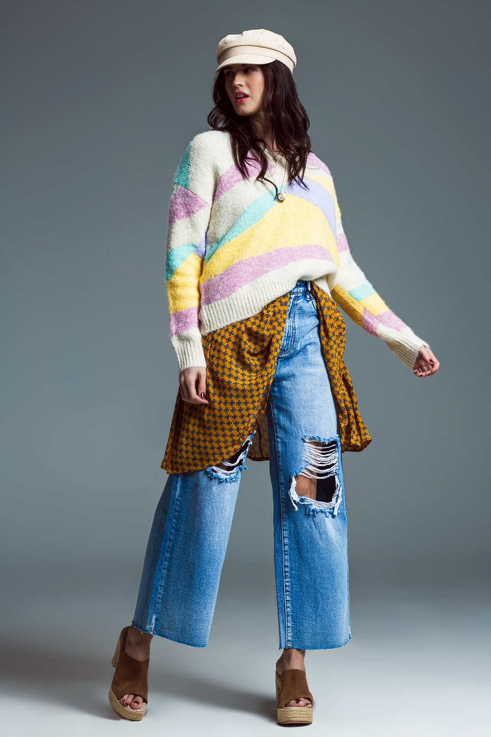 Outfit casual de mujer con jersey colorido oversize, vaqueros anchos desgastados y sandalias de plataforma.