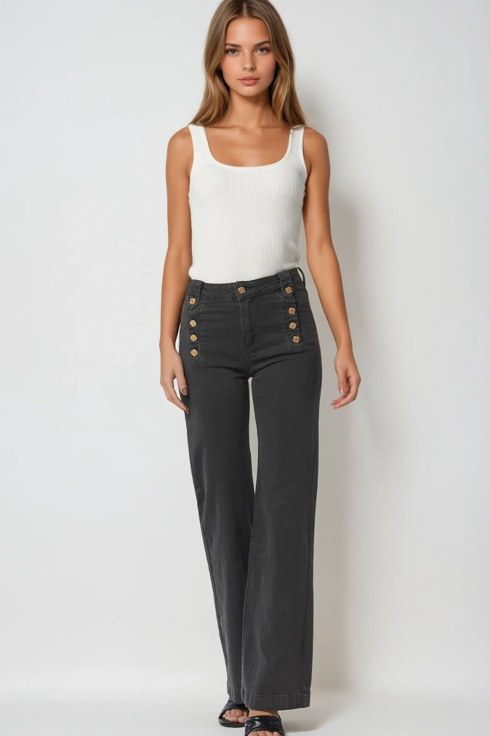 Modelo luciendo un pantalón vaquero ancho de estilo marinero con talle alto y botones dorados.