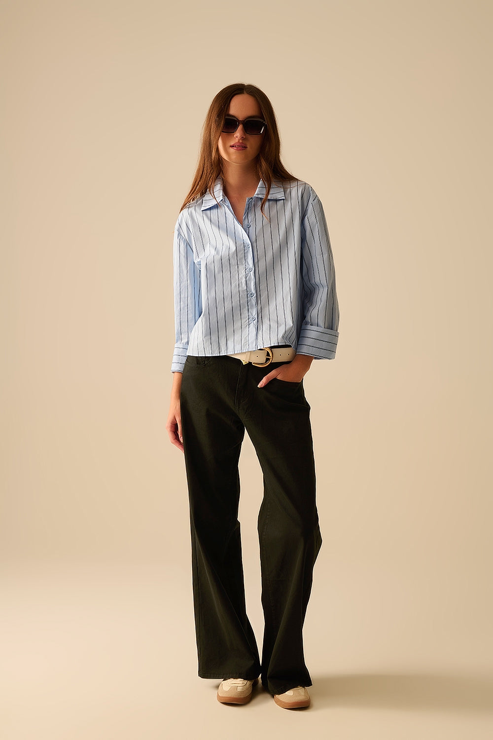 Modelo con pantalón negro de corte recto y talle alto, confeccionado en algodón elástico.