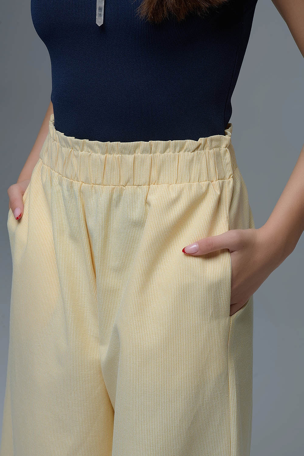 Pantalón ancho de mujer en color amarillo claro con rayas finas, talle alto elástico y bolsillos.