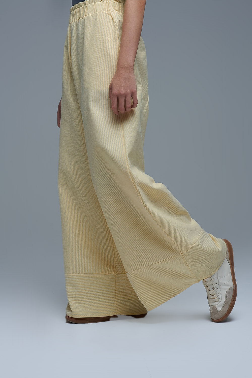 Pantalón ancho de mujer en color amarillo claro con rayas finas, talle alto elástico y bolsillos.