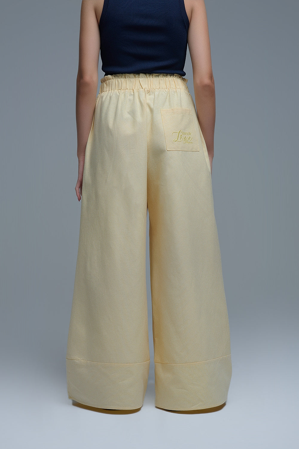 Pantalón ancho de mujer en color amarillo claro con rayas finas, talle alto elástico y bolsillos.