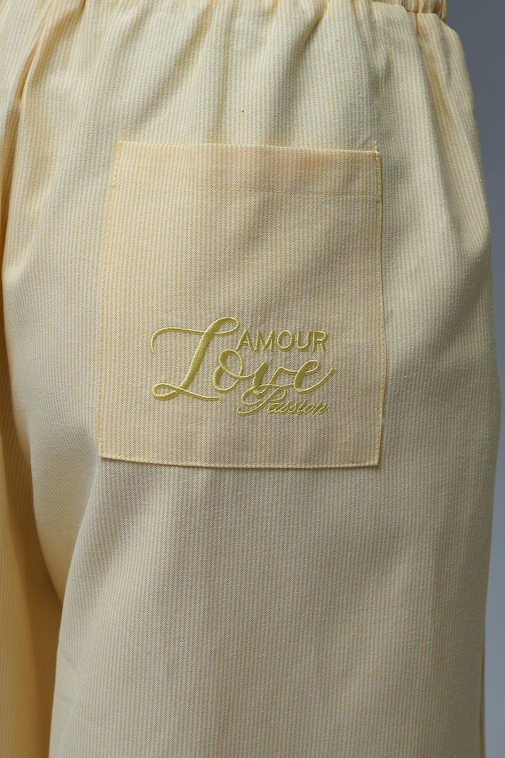 Pantalón ancho de mujer en color amarillo claro con rayas finas, talle alto elástico y bolsillos.