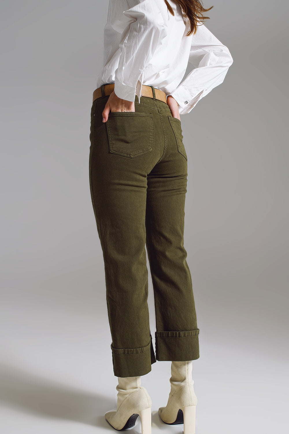 vaqueros rectos color verde oscuro con bajo de vuelta ancha y botines crema.