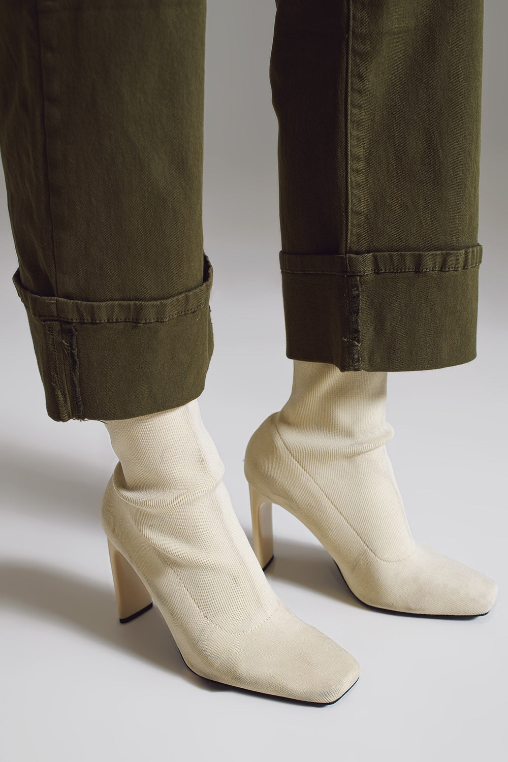 vaqueros rectos color verde oscuro con bajo de vuelta ancha y botines crema.