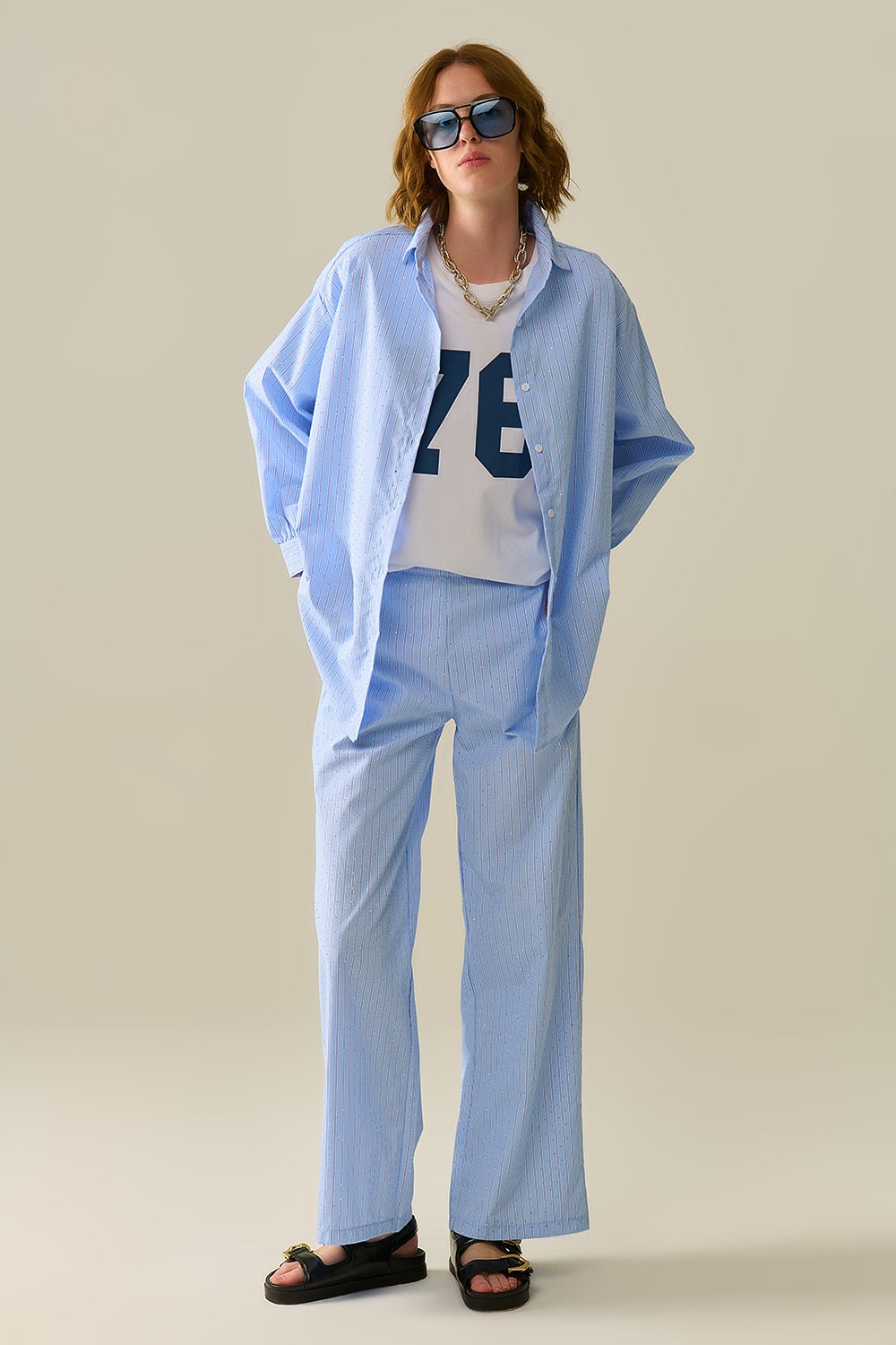 Pantalones anchos con rayas verticales y detalles brillantes combinados con camiseta blanca