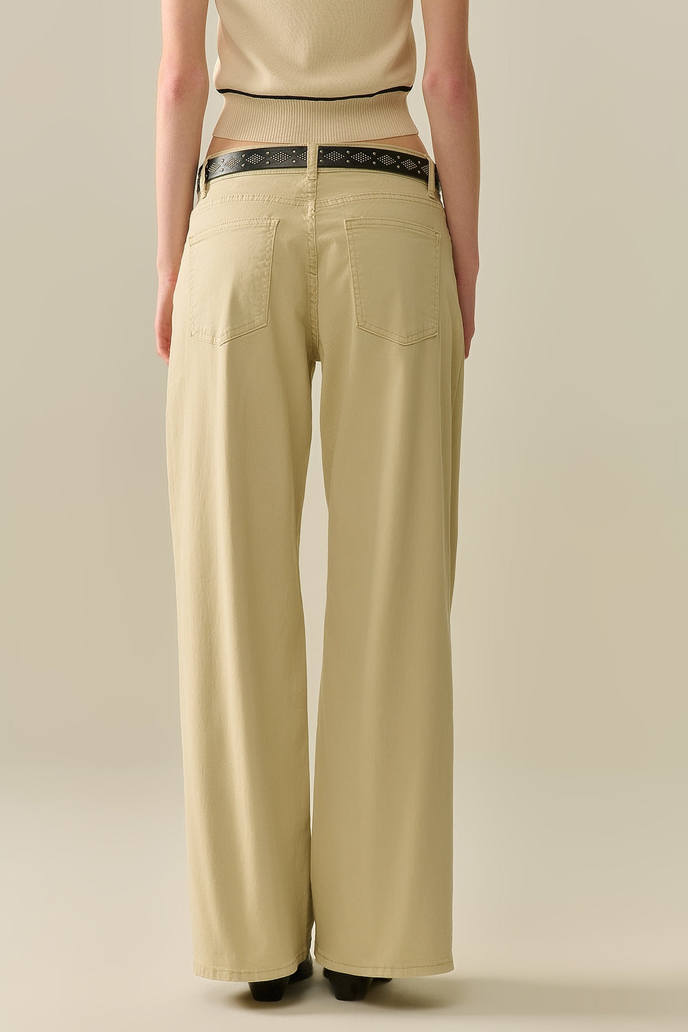 Vista trasera de un pantalón de pernera ancha en color beige mostrando la caída del tejido.