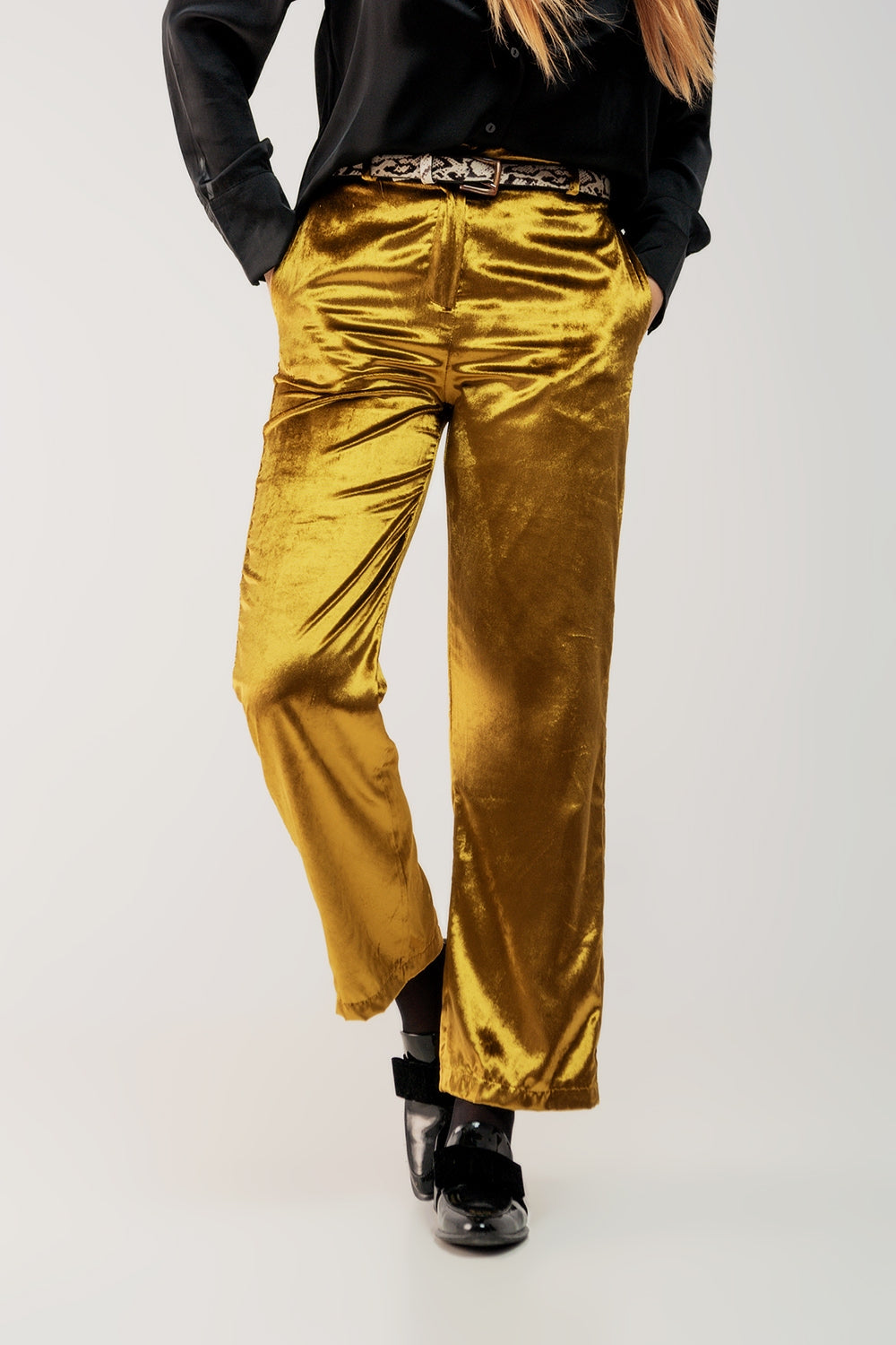 Primer plano mostrando la textura brillante y el color lima dorado de unos pantalones de terciopelo.