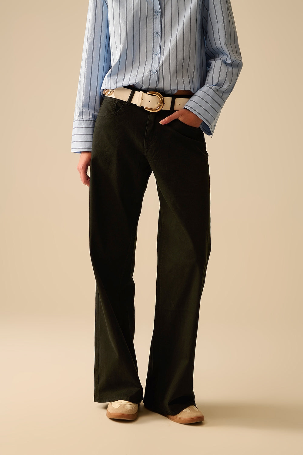 Modelo con pantalón negro de corte recto y talle alto, confeccionado en algodón elástico.
