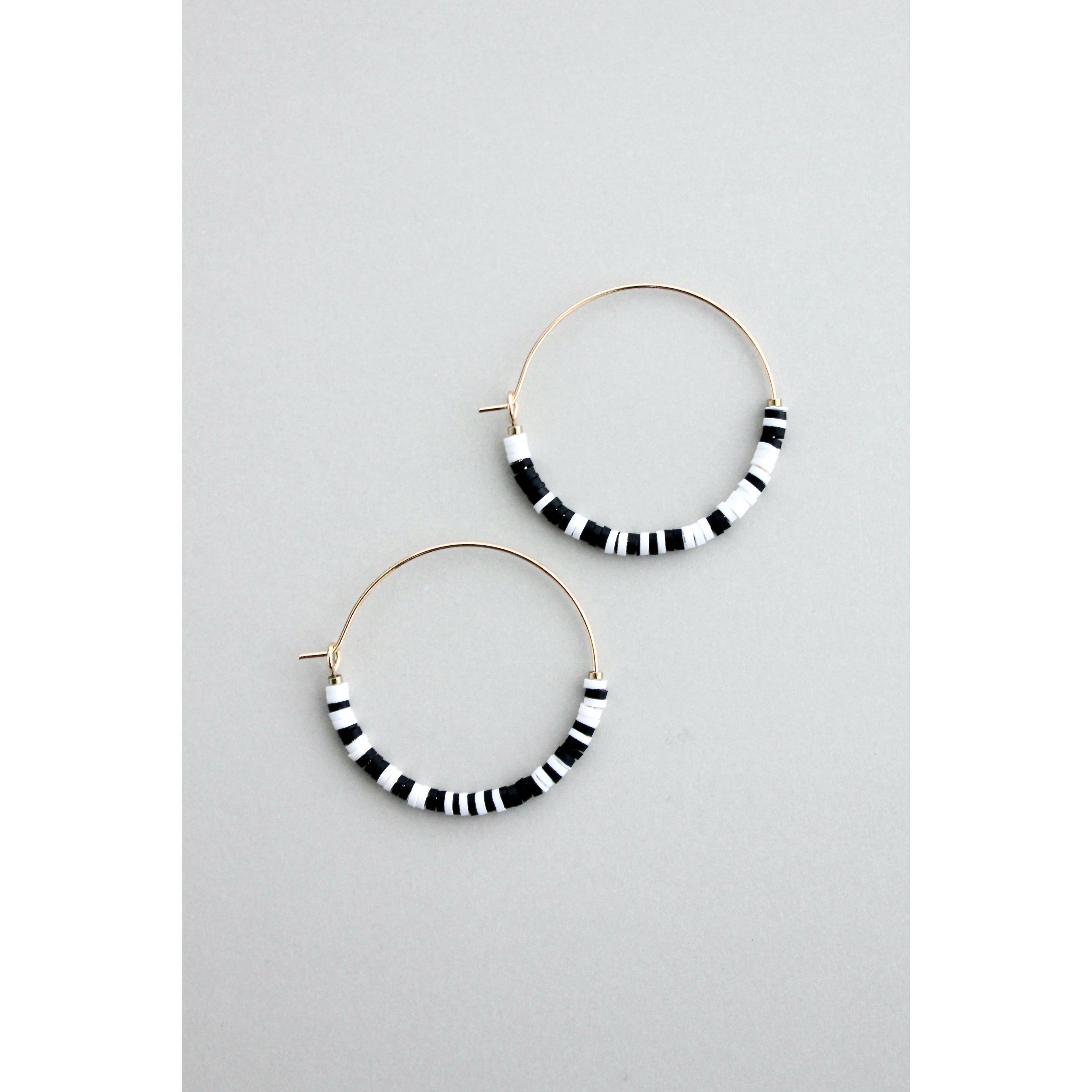 Pendientes de aro con cuentas Miyuki blancas y negras sobre fondo gris, diseño ligero y dorado de David Aubrey.